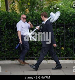 Un employé de bureau porte un grand fan à Westminster, dans le centre de Londres. Le met Office a publié un avertissement météorologique ambre pour une chaleur extrême dans certaines parties du Royaume-Uni, en prévision de nouvelles températures en hausse cette semaine. Date de la photo: Mardi 12 juillet 2022. Banque D'Images