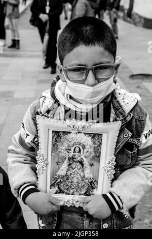 Un jeune garçon tient une image de la Vierge Marie lors D'Un festival religieux, Plaza de Armas, Puno, province de Puno, Pérou. Banque D'Images