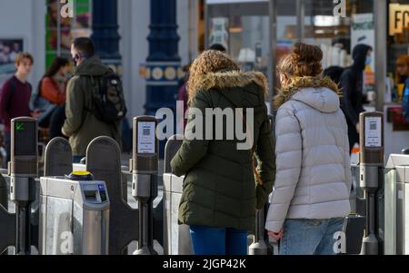 Les passagers franchissant des barrières tarifaires à la gare de Brighton, en Angleterre. Banque D'Images