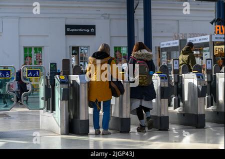 Les passagers franchissant des barrières tarifaires à la gare de Brighton, en Angleterre. Banque D'Images