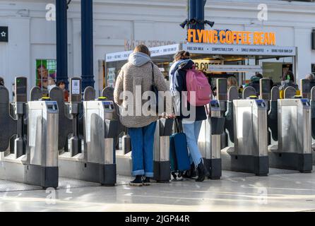 Les passagers franchissant des barrières tarifaires à la gare de Brighton, en Angleterre. Banque D'Images