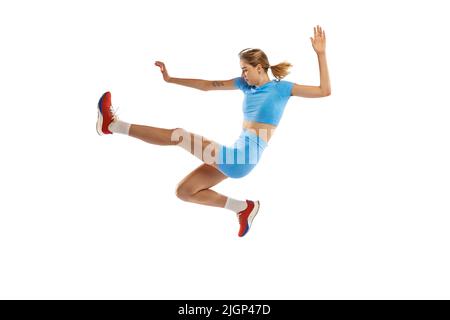 Technique de triple saut. Photo de studio d'une athlète féminine en uniforme sportif sautant isolé sur fond blanc. Concept de sport, d'action, de mouvement, de vitesse. Banque D'Images