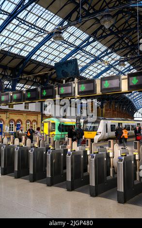 Les passagers franchissant des barrières tarifaires à la gare de Brighton, en Angleterre. Banque D'Images