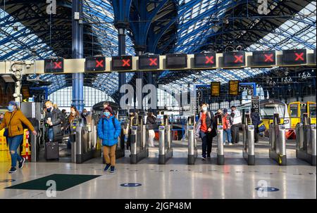 Les passagers franchissant des barrières tarifaires à la gare de Brighton, en Angleterre. Banque D'Images