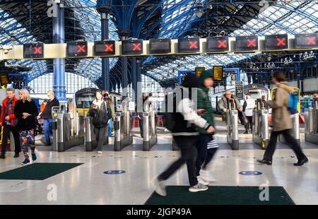 Les passagers franchissant des barrières tarifaires à la gare de Brighton, en Angleterre. Banque D'Images