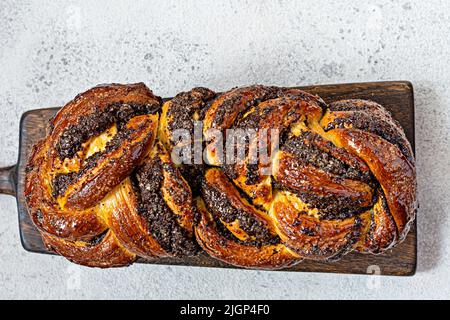 Brioche/Babka fraîchement cuite avec graines de pavot et chocolat sur une planche en bois. Pain de dessert tressé. Pâtisserie maison, pâtisseries nationales. Krin estonien Banque D'Images