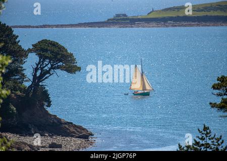 Un bateau à voile classique navigue dans des eaux étincelantes en direction de Cow's Beach et de la mer ouverte de Durgan sur la rivière Helford dans les Cornouailles. Banque D'Images