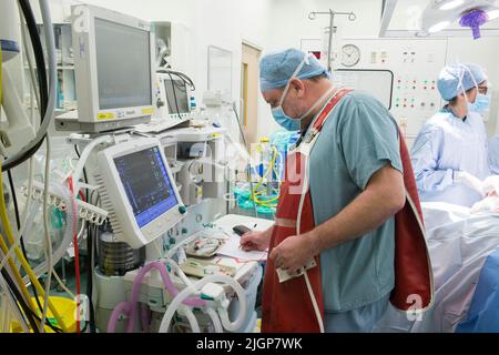 Un anesthésiste vérifie la progression du patient pendant une opération de l'hôpital NHS. Banque D'Images