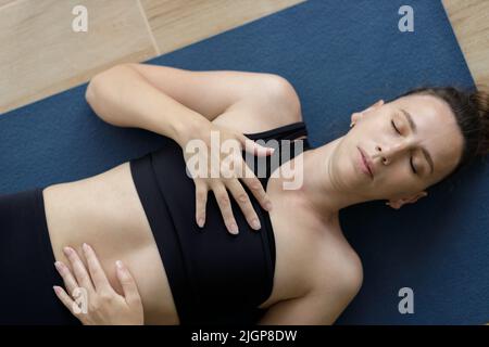 Vue rapprochée en haut de la jeune femme méditant dans le shavasana posture du yoga Banque D'Images