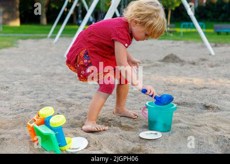 Petit enfant jouant avec du sable et des jouets dans le parc. Petit enfant sur le terrain de jeu en été Banque D'Images