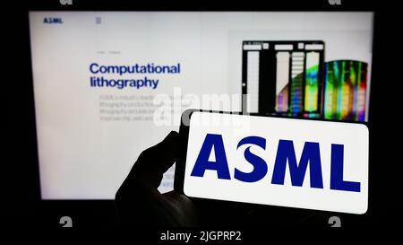 Personne tenant un smartphone avec le logo de la société néerlandaise de semi-conducteurs ASML Holding N.V. à l'écran devant le site Web. Mise au point sur l'affichage du téléphone. Banque D'Images