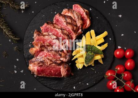 Côtelettes de veau en tranches servies sur une assiette d'ardoise accompagnée de frites et de poivrons Banque D'Images