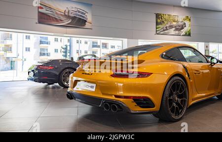 Une photo d'une Porsche 911 Turbo S orange à l'intérieur d'une concession. Banque D'Images