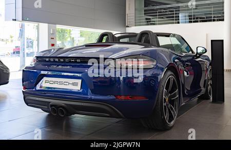 Une photo d'une Porsche 718 Boxster bleu foncé à l'intérieur d'une concession. Banque D'Images