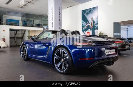 Une photo d'une Porsche 718 Boxster bleu foncé à l'intérieur d'une concession. Banque D'Images