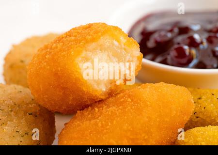 Gros plan des nuggets au fromage pané frits avec de la sauce aux baies de lingonis. Banque D'Images