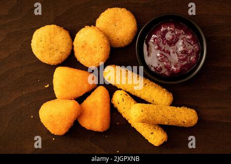 Beignets de brie panée et de camembert, bâtonnets de mozzarella et sauce aux baies de lingonis sur bois sombre. Vue de dessus. Banque D'Images