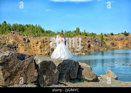 Un homme et une femme, la mariée et le marié sont debout sur une immense pierre sur fond d'eau bleue, des montagnes partout. ukraine 2022 Banque D'Images