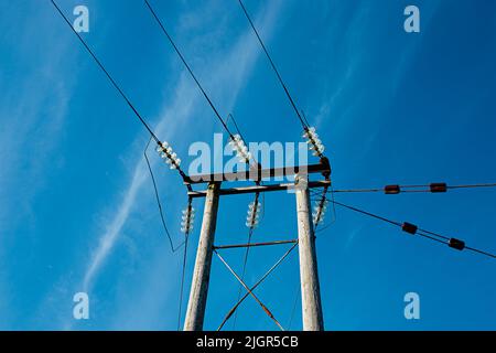 Pylône de service public (électricité) placé contre un ciel bleu clair Banque D'Images