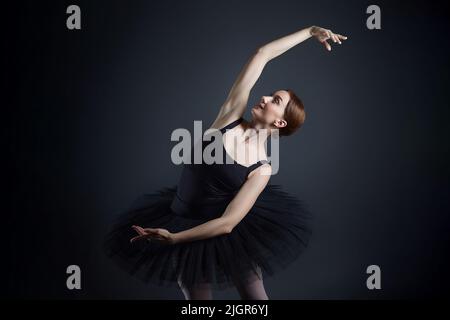 la ballerine élégante a fait une déflexion. la photo prend dans le studio sur un fond sombre. Banque D'Images