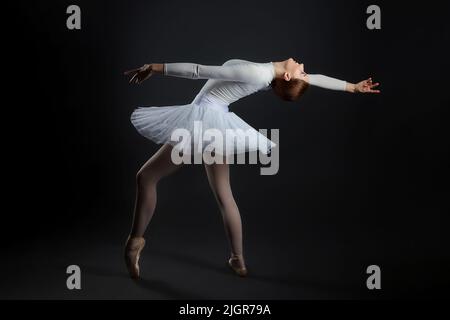 la ballerine élégante a fait une déflexion. la photo prend dans le studio sur un fond sombre. Banque D'Images