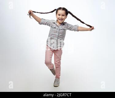 charmante petite fille avec des picots tressés dans le studio sur fond blanc. Banque D'Images