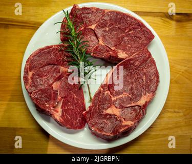 Trois steaks de côtes de bœuf sur fond de bois Banque D'Images
