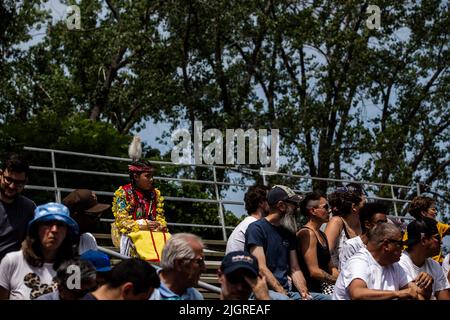 Kahnawake, Canada. 10th juillet 2022. Les gens regardent les danseurs de Pow-wow portant des costumes traditionnels pendant le festival. Les échos annuels 30th d'un pow-wow de la nation fière ont amené des milliers de personnes de toute l'Amérique du Nord à célébrer la culture et les traditions des Autochtones dans la réserve mohawk de Kahnawake. Après un hiatus de deux ans, le plus grand pow-wow du Québec a offert un temps pour se rencontrer, danser, chanter, visiter et célébrer avec des amis et la famille. Crédit : SOPA Images Limited/Alamy Live News Banque D'Images