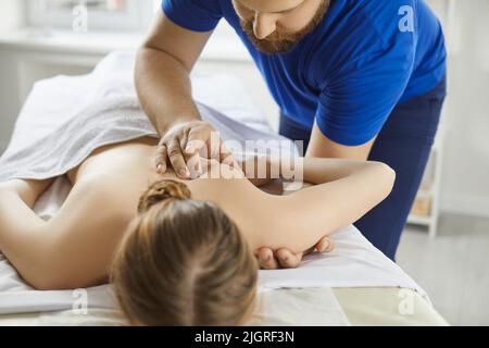 Femme se réoffrant un massage de scapula pendant un traitement de physiothérapie à la clinique moderne Banque D'Images