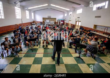 Un professeur de musique dirige l'orchestre étudiant d'une école paroissiale de Santa Ana, CA. Banque D'Images