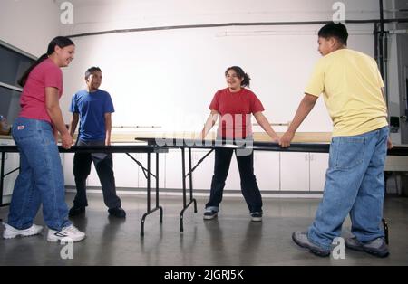 Les étudiants hispaniques de physiographie utilisent des tables pliantes se chevauchant pour démontrer le mouvement des plaques techtoniques comme la cause des tremblements de terre. Banque D'Images