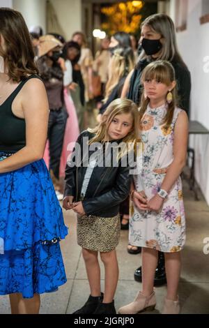 Coulisses, les modèles jeunes et vieux attendent de faire leur entrée à un défilé de mode à Costa Mesa, CA. Banque D'Images