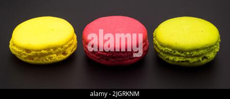 Trois macarons colorés sur fond noir dans une photo panoramique Banque D'Images