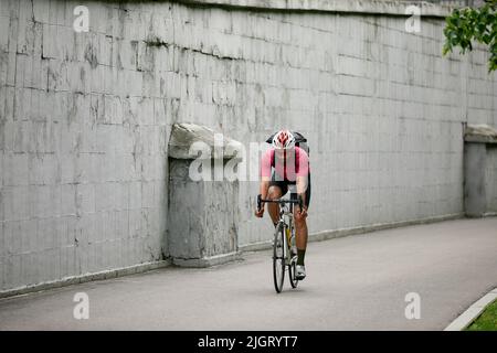 Homme élégant marchant dans la ville à vélo le week-end, sur un fond de mur gris. Photo minimaliste du cycliste sur un fond de Banque D'Images