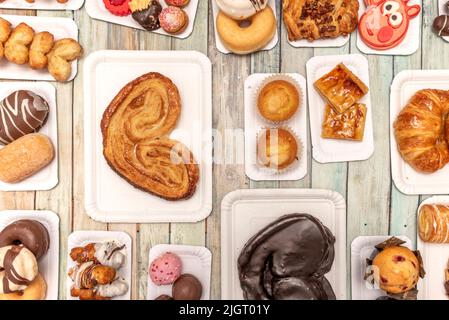 Ensemble de plateaux en carton blanc avec bonbons, desserts et palmiers au chocolat, muffins, beignets au chocolat, boules de chocolat et noix de coco et palmier à sucre Banque D'Images