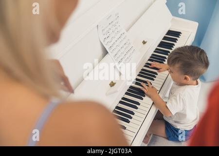 parents regardant leur petit fils jouer le concept de famille de piano. Photo de haute qualité Banque D'Images