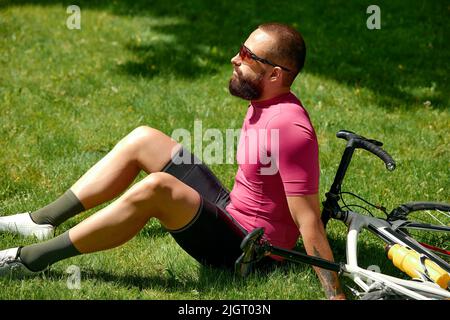 Cycliste prenant le repos dans les herbes vertes. L'été, bonne humeur. Banque D'Images