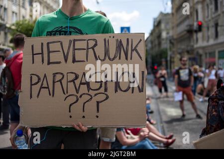 Budapest, Hongrie. 12th juillet 2022. Un manifestant tient un écriteau lors de la manifestation à Budapest. Des centaines de personnes ont protesté contre la modification de la loi sur la taxe Itemized pour les petites entreprises (« KATA » pour le moins en hongrois), Le nouveau projet d'amendement proposé par le gouvernement de Viktor Orban vise à renforcer l'admissibilité à un régime fiscal simplifié auquel de nombreuses petites entreprises ont opté en raison de l'administration allégée et du faible taux d'imposition. Des manifestants bloquent toujours le pont de Margaret sur le Danube, à côté du Parlement. Crédit : SOPA Images Limited/Alamy Live News Banque D'Images