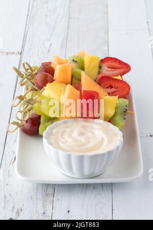 Brochettes de fruits frais sur un plateau servi avec une sauce au yaourt, prêt à manger. Banque D'Images