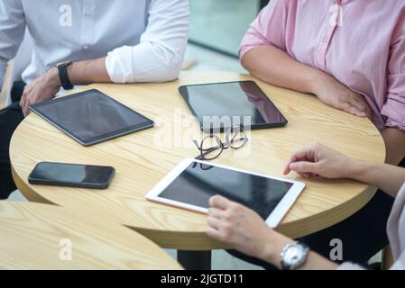 Tablettes numériques et smartphone sur table ronde avec les professionnels assis. Vue de dessus et vue rapprochée. Banque D'Images
