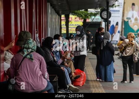 Bandung, Java-Ouest, Indonésie. 13th juillet 2022. Les femmes portant un masque de protection sont vues assis comme elles attendent un bus à Bandung. Le président indonésien Joko Widodo a demandé au public de porter des masques à l'intérieur comme à l'extérieur, ce qui est lié à la propagation croissante du virus Covid-19 en Indonésie. Les politiques de voyage ont également été renforcées, comme les exigences obligatoires pour les vaccins de rappel pour voyager, entrer dans un certain nombre d'installations publiques, des bureaux, des attractions touristiques, des centres commerciaux ou des centres commerciaux. (Image de crédit : © Algi Febri Sugita/ZUMA Press Wire) Banque D'Images