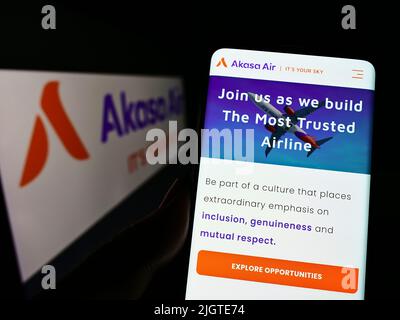 Personne tenant un téléphone portable avec la page Web de la compagnie aérienne SNV Aviation Private Limited (Akasa Air) à l'écran avec le logo. Concentrez-vous sur le centre de l'écran du téléphone. Banque D'Images