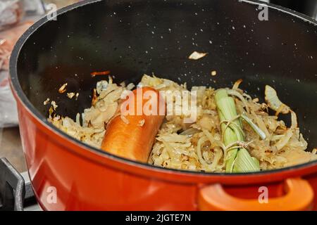 Saucisse fumée et chou dans une casserole avec un bouquet de légumes verts pour faire de la choucroute alsacienne Banque D'Images