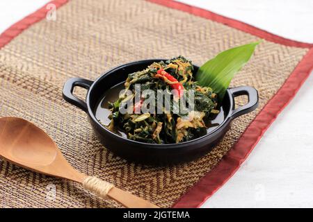 Sautés feuilles de papaye ou Tumis Daun Pepaya fait de papaye bouillie ou de feuilles de manioc aux épices et au Chili. Ajoutez généralement des anchois frits. Parfois ca Banque D'Images