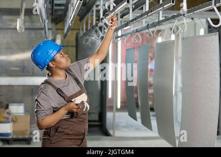 Femme africaine travaillant dans une usine industrielle et accrochant des produits finis sur un rack Banque D'Images