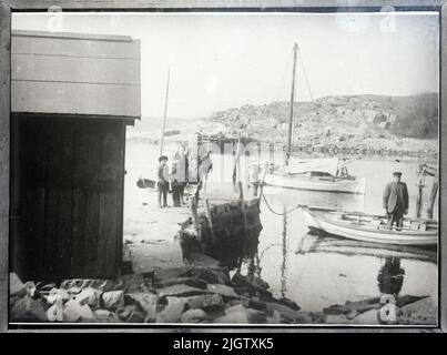 Selon des notes ultérieures: 'Fågelviken, à partir du 1920s'. Une femme plus âgée, et quatre enfants, se tient dans une grappe sur un quai, à droite d'une hangar à bateaux. Dans l'eau est un voilier et un chêne. Dans le chêne, un homme est en train d'ajouter ou de poster? Reproto d'une photo. Banque D'Images