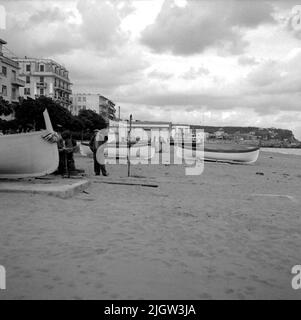 23. Italie. Le journal photo est disponible à B.M.A. + albums photo. Acquisition : livres et documents d'archives. Photos prises 1959-11-04,11 photos en série. Selon les notes: Italie. Golfe, Albisssola, 4/11 -59. Bateaux sur la plage. Plusieurs bateaux sont commandés sur une plage. Un homme se tient à l'un des bateaux. Au-dessus de la plage est une société. Banque D'Images