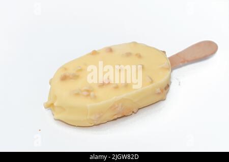 Bâton de glace à la vanille enrobé et recouvert d'une couche de chocolat blanc avec des noix, glace riche aromatisée à la vanille en chocolat blanc craquant et Banque D'Images