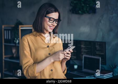 Portrait d'une fille gaie et attirante, experte en utilisant un appareil gadget développement de projet Web sur le lieu de travail à l'intérieur de la station de travail Banque D'Images