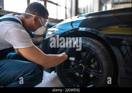 Un spécialiste expérimenté de l'auto-finition applique le brillant du pneu avant le polissage de la voiture Banque D'Images